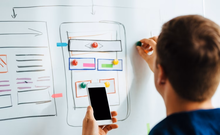 A designer making an app plan on a whiteboard